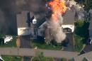 In this frame grab from television helicopter video, a police SWAT team, left, is parked on the lawn of a home in Brentwood, N.H., as it explodes in flames, Monday May 12, 2014. Shots were fired just before the fire, which involved a police officer, according to the New Hampshire State Police. (AP Photo/WCVB-TV 5) TV OUT
