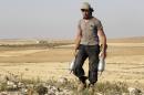 An Islamist rebel fighter carries mortar shells in the Hama countryside