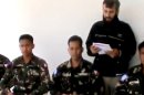 In this image taken from video obtained from the Ugarit News, which has been authenticated based on its contents and other AP reporting, a man reads a statement as four abducted Filipino UN peacekeepers are seen in Daraa, Syria, on Thursday, May 9, 2013. Tensions remained high on the Israeli-Syrian border on Thursday morning, two days after a Syrian rebel group abducted four UN peacekeepers. The abduction was the second such incident in the area in two months. The UN said the Filipino peacekeepers were detained on Tuesday while on patrol on the Golan Heights, a volatile Israeli-occupied area that separates Syria and Israel. (AP Photo/Ugarit News via AP video)