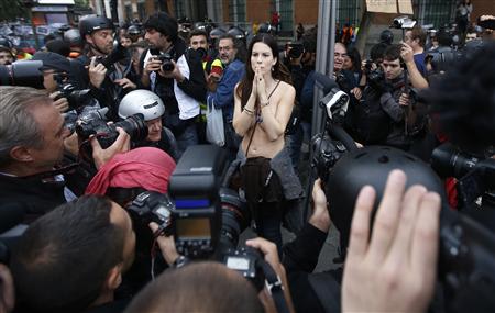 A topless protester is surrounded by cameramen during an anti-austerity demonstration outside the Spanish parliament in Madrid