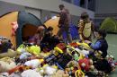 Boys play with toys distributed by volunteers as family members sit outside their tents at the Galatsi Olympic Hall in Athens, Wednesday, Nov. 4, 2015. The disused facility, which used during the Athens Olympics 2004, reopened a month ago for migrants as more than 600,000 people have arrived in Greece so far this year trying to head for more prosperous European Union countries in the north. (AP Photo/Thanassis Stavrakis)