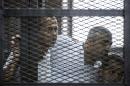 Al-Jazeera reporters Peter Greste (L), Mohamed Fahmy (C) and Baher Mohamed follow their trial proceedings from the defendants cage on June 23, 2014 at the police institute in Cairo