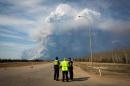 Officers look on as smoke from Fort McMurray's raging wildfires billow into the air after their city was evacuated