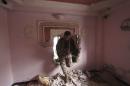 A rebel fighter moves through a hole in a wall inside a house north of Handarat camp in Aleppo