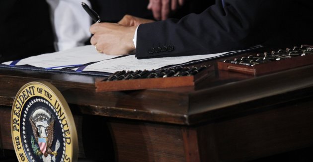 FILE - This March 23, 2010 file photo shows Ttwenty two pens next to President Barack Obama as he signs the health care reform bill in the East Room of the White House in Washington. Your medical plan is facing an unexpected expense, so you probably are, too. It's a new, $63-per-head fee to cushion the cost of covering people with pre-existing conditions under President Barack Obama’s health overhaul. The charge, buried in a recent regulation, works out to tens of millions of dollars for the largest company health plans, and much of that is likely to be passed on to employees. Multiple pens are used to sign legislation, and then distributed to supporters of the legislation. (AP Photo/Charles Dharapak, File)