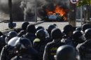A vehicle burns near riot policemen during a protest near where the Confederations Cup semi-final match between Spain and Italy is being played, in Fortaleza