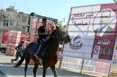 A boy rides a horse past an election campaign poster in the Jordanian capital Amman on September 14, 2016 ahead of the general elections to be held on September 20