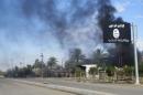 Smoke raises behind an Islamic State flag after Iraqi security forces and Shiite fighters took control of Saadiya from Islamist State militants