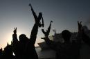 Rebel fighters hold their weapons aloft to welcome a Turkish ship arriving from Misrata to the port of Benghazi to evacuate the wounded on April 3, 2011