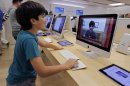 In this Thursday, July 19, 2012, photo an Apple customer Shayan Hooshmand, 11, uses PhotoBooth on a 21.5-inch iMac at an Apple store in Palo Alto, Calif. Apple Inc. reports quarterly financial results after the market closes on Tuesday, July 24. (AP Photo/Paul Sakuma)