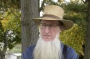 FILE - In an Oct. 10. 2011 file photo, Sam Mullet Sr., the leader of a breakaway Amish group, stands in the front yard of his Bergholz, Ohio home. Mullet and 15 other Amish men and women are to go on trial Monday, Aug. 27, 2012, in Cleveland on charges of carrying out hate crimes in the hair-cutting attacks. Other charges include conspiracy, evidence tampering and obstruction of justice in what prosecutors say are crimes motivated by religious differences. They could face lengthy prison terms if convicted.( AP Photo/Amy Sancetta, File)