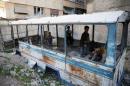 Children play in a damaged school bus in the rebel held besieged town of Jesreen, in the eastern Damascus suburb of Ghouta, Syria