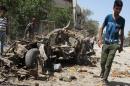 An Iraqi youth walks past the remains of a vehicle at the site of an explosion in Baghdad on April 9, 2014