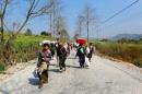 Refugees who have been displaced by recent violence, walk down a road with bundles of belongings, in Laukkai