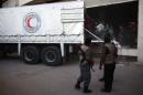 Syrian rebel fighters stand guard as sacks of aid are unloaded from a Syrian Arab Red Crescent truck in the eastern Ghouta region, on March 7, 2016 during a UN-led operation to deliver food