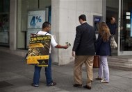 A man hands out leaflets advertising the buying or selling of watches, gold, and diamonds in front of a bank branch in central Madrid, June 19, 2012. REUTERS/Paul Hanna
