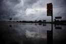 Storm clouds are reflected in the flooded parking lot of a gas station in Level Plains, Ala. after heavy rains moved through the area Sunday, June 10, 2012. (AP Photo/Dothan Eagle, Max Oden)