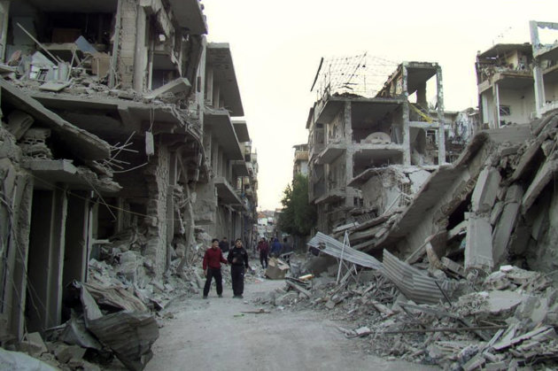 In this citizen journalism image provided by the Homs City Union of The Syrian Revolution, which has been authenticated based on its contents and other AP reporting, Syrian citizens walk in a destroyed street that was attacked on Wednesday by Syrian forces warplanes, at Abu al-Hol street in Homs province, Syria, Thursday Nov. 29, 2012. Two US-based Internet-monitoring companies say Syria has shut off the Internet nationwide. Activists in Syria reached Thursday by satellite telephone confirmed the unprecedented blackout, which comes amid intense fighting in the capital, Damascus.(AP Photo/Homs City Union of The Syrian Revolution)