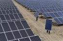 Employees carry solar panels at a solar power plant in Aksu