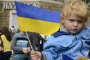 A boy holds a Ukrainian flag as soldiers parade in Mariupol during the celebrations marking the city day on September 20, 2014