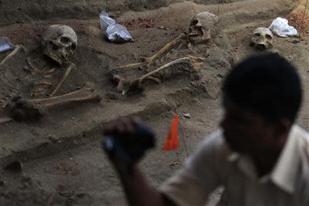 A police officer takes a video of human skeletons at a construction site in the former war zone in Mannar