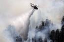 A firefighting helicopter drops water near Camp Bravo summer camp as firefighters battle the Lake Fire in the San Bernardino National Forest, California