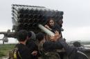 Rebel fighters of the Al-Furqan brigade prepare Grad rockets to be launched towards forces loyal to Syria's President Bashar Al-Assad stationed in Salhab village, from the orchards of the west of al-Zukat village