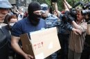 Russian security servicemen leave with items from opposition leader and anti-corruption blogger Navalny's apartment in Moscow