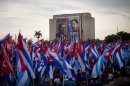 People carry Cuban flags during the annual May Day march near a building covered with an image of Venezuela's late President Hugo Chavez, right, and late Cuban union leader Lazaro Pena in Revolution Square in Havana, Cuba, Wednesday, May 1, 2013. Workers held protests, parades, strikes and other demonstrations in cities across the world on Wednesday. (AP Photo/Ramon Espinosa)