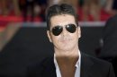 Television mogul Simon Cowell poses for photographers as he arrives for the film "One Direction: This is Us", in London