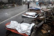 A woman stands in front of her husband's dead body on a street in Tacloban, eastern island of Leyte on November 10, 2013