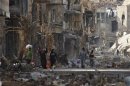 Residenti e combattenti ribelli siriani lungo una strada tra edifici danneggiati a Deir al-Zor