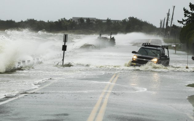 A truck drives through water pushed over a road by Hurricane Sandy in Southampton