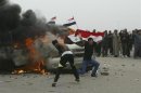 A protester throws rocks and shouts slogans in front of a burning vehicle during clashes with security forces in Falluja