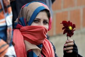 A migrant holds a flower as she waits for buses at Miratovac village