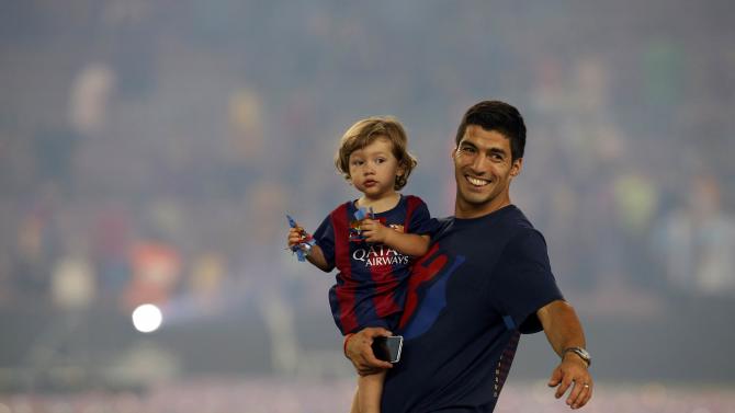 Barcelona&#39;s Suarez holds his son Benjamin after the celebration parade in Barcelona