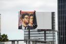 Workers remove a poster-banner for "The Interview" from a billboard in Hollywood, California, December 18, 2014 a day after Sony announced it had no choice but to cancel the movie's Christmas release and pull it from theaters due to a credible threat