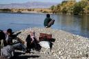 Syrian Kurds wait along the river close to the town of Semalka in northeast Syria on October 21, 2013