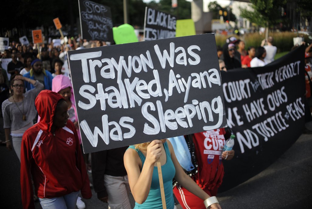 Protesters make their way down Washington Ave., from Grand Circus Park in Detroit to the Federal Building during a protest against the verdict in the trial of George Zimmerman for the killing of unarmed teenager Trayvon Martin in Florida on Sunday, July 14, 2013. The Aiyana in the sign refers to young Detroiter Aiyana Stanley-Jones, who was killed during a police raid. (AP Photo/Detroit News, Elizabeth Conley)