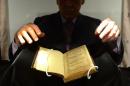 A Sotheby's employee handles a copy of the Â“Bay Psalm Book during a preview at SothebyÂ’s in New York, April 12, 2013