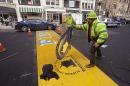 Eric House lifts off a BAA logo stencil while applying a fresh coat of paint to the Boston Marathon finish line on Boylston Street in Boston, Tuesday, March 25, 2014. The 118th running of the Boston Marathon is scheduled for April 21, 2014. (AP Photo/Stephan Savoia)