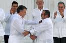 Colombian President Juan Manuel Santos (L) and the head of the FARC guerrilla Timoleon Jimenez, aka Timochenko, shake hands during the signing of the historic peace agreement in Cartagena