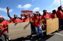 Workers on strike hold signs as they take part in a demonstration outside Ford's plant in Pretoria on August 20, 2013