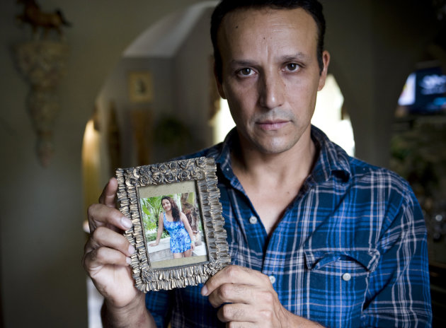 This Aug. 14, 2012 photo shows Rony Molina holding a photo of his wife in his home in Stamford, Conn. Molina's wife, Sandra Payes Chacon, was deported to Guatemala in 2010, leaving Molina alone to care for their three children, all American citizens. (AP Photo/Jessica Hill)