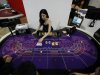 In this photo taken on Thursday, May 23, 2013, an attendant demonstrates the game of baccarat on a baccarat gaming table during the Global Gaming Expo Asia in Macau. Almost all of Macau’s $38 billion in gambling revenue last year - six times more than the Las Vegas Strip - came from card game, much of it from Chinese high-rollers betting borrowed money and dwarfing the takings from slots, blackjack or roulette. Wherever you go in the former Portuguese colony, you’ll see chain-smoking Chinese gamblers crowded around baccarat tables as players peel back their cards, hoping their luck will give them a good hand. (AP Photo/Kin Cheung)