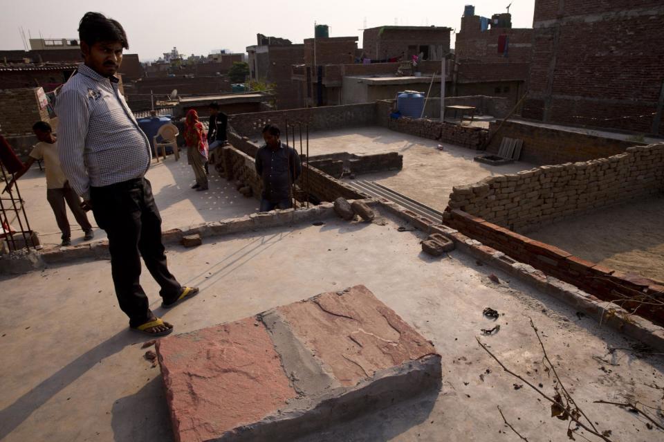Relatives stand on the terrace of a house where a 15-year-old girl was set on fire after being raped at Tigri village, near Noida, a suburb of New...