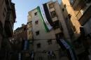 Syrian erect a pre-Baath Syrian flag, that was adopted by the Syrian revolution during the uprising, on top of a building in the northern Syrian city of Aleppo on March 15, 2015, to mark the fourth anniversary of Syria's conflict