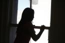 Maria, an undocumented migrant from Central America, looks out of a window in Los Angeles
