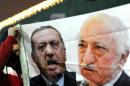 A picture taken on December 30, 2013 shows a Turkish protester (L) holding up a banner with pictures of Recep Tayyip Erdogan (C) and Fethullah Gulen (R) during a demonstration against the goverment in Istanbul