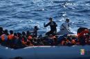 Migrants sit in their rubber dinghy during a rescue operation by Italian navy ship Borsini off the coast of Sicily